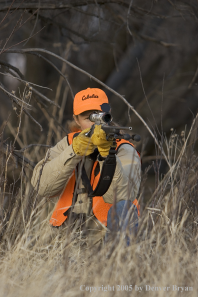 Woman big game hunter aiming/firing for game.