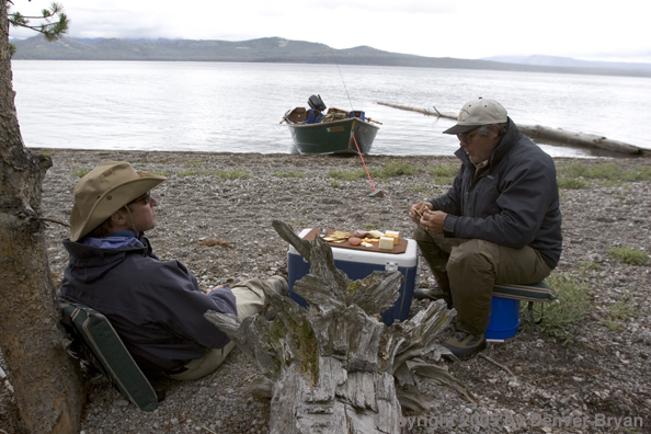 Flyfishermen eating lunch on shore of lake.