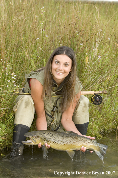 Woman flyfisher with large brown trout.