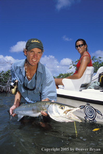 Saltwater flyfisherman with barricuda, woman on boat.