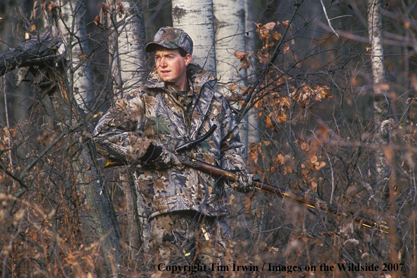 Flintlock rifle hunter in woods.