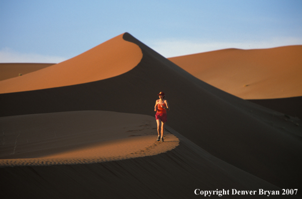 Woman running on sand dunes in Sossusvlei park, Namibia. Africa