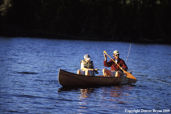 Father and son fishing from cedar canoe.