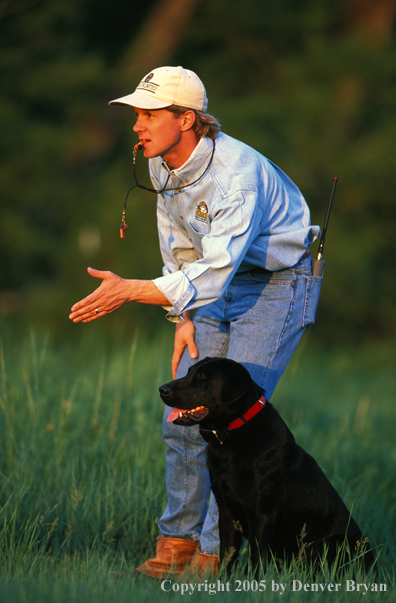 Trainer with black Labrador Retriever.