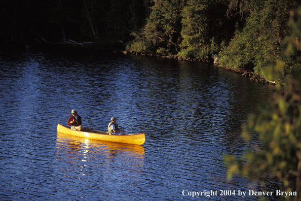 Father and son fishing from cedar canoe.