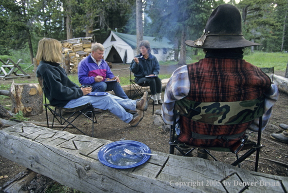 Cowboys and campers sitting around campfire.