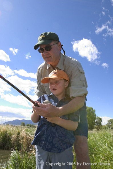 Father helping son spincast fishing.