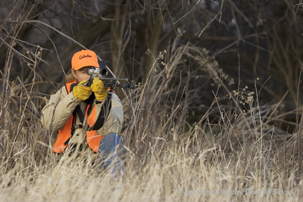 Woman big game hunter aiming/firing for game.