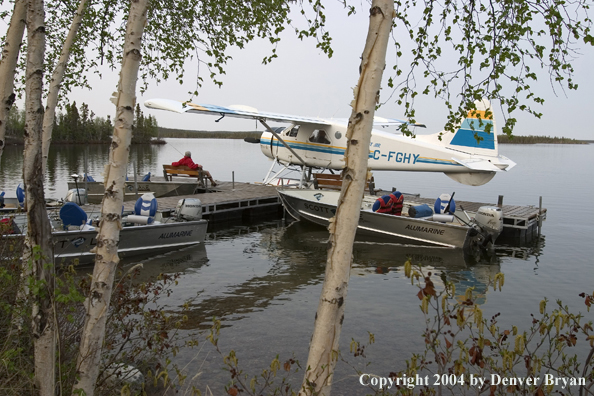 Fisherman with float plane and fishing boats tied up to the dock at dusk.  Saskatchewan.