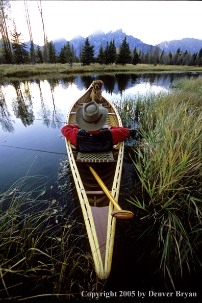 Flyfisherman with Golden Retriever in wooden cedar canoe.  