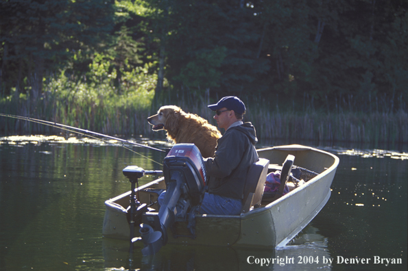 Spincast fisherman in boat with Golden Retriever