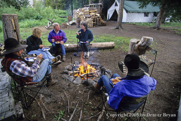 Cowboys and campers sitting around campfire.