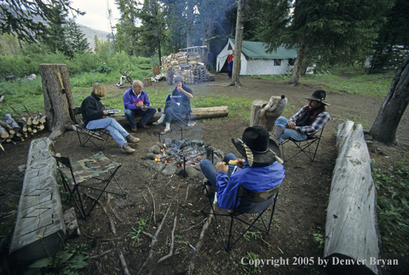 Cowboys and campers sitting around campfire.