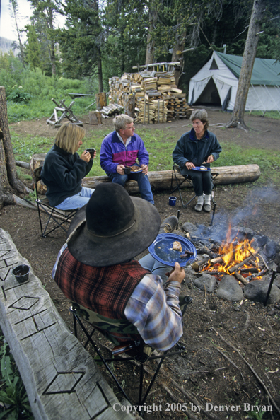 Cowboys and campers sitting around campfire.