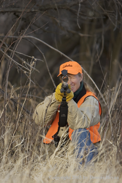 Woman big game hunter aiming/firing for game.