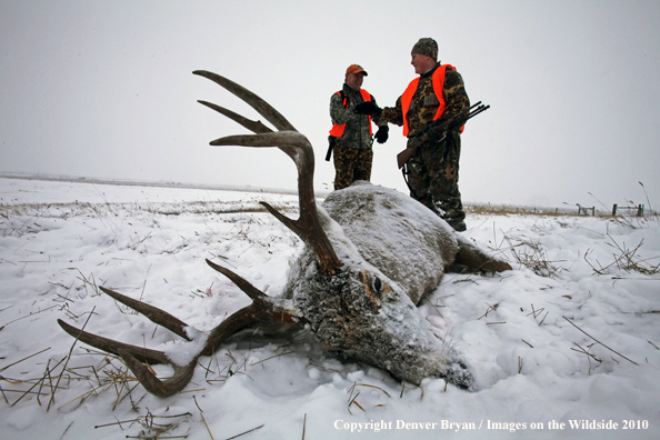 Father and son walking up on son's downed white-tail buck 