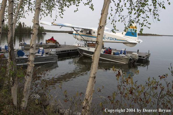 Fisherman with float plane and fishing boats tied up to the dock at dusk.  Saskatchewan.