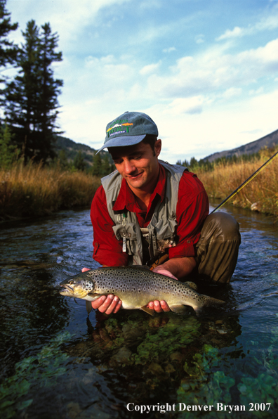 Flyfisherman holding brown trout.