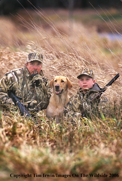 Father and son duck hunters and yellow Labrador Retriever.