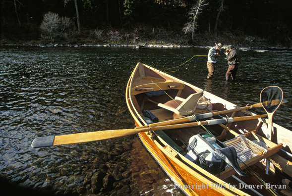 Fly fisherman with guide tying flies.  Driftboat in foreground.