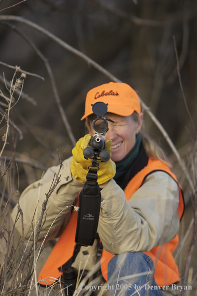 Woman big game hunter aiming/firing for game.