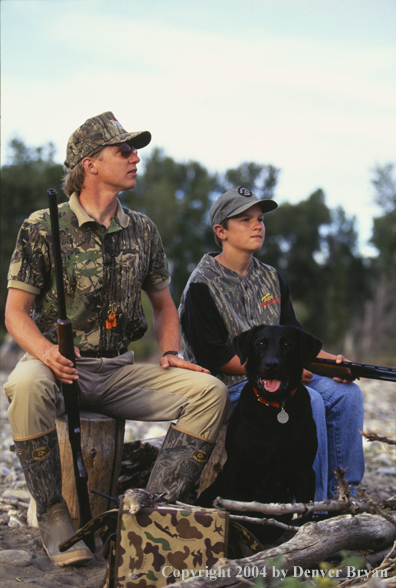 Father and son dove hunting with Labrador Retriever.