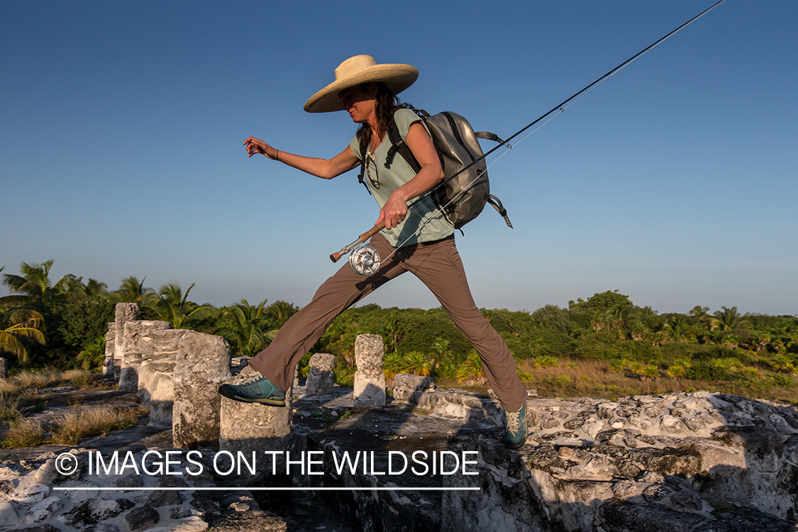 Flyfishing woman walking through ruins to fishing location.