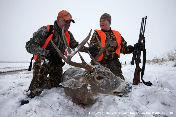 Father and son posing with son's downed white-tail buck 