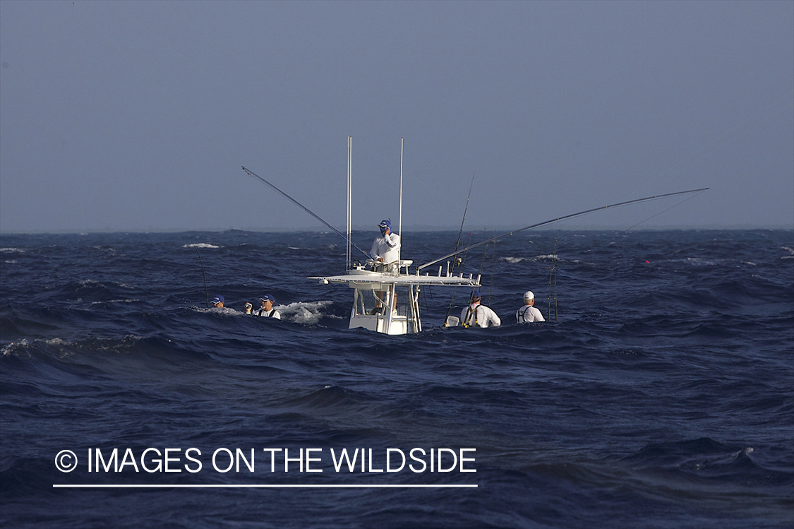 Fishermen on deep sea fishing boat with wave on foreground.