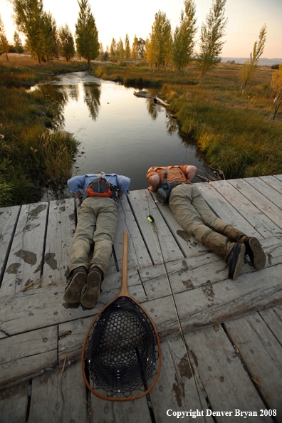 Flyfishermen peaking over creek bridge