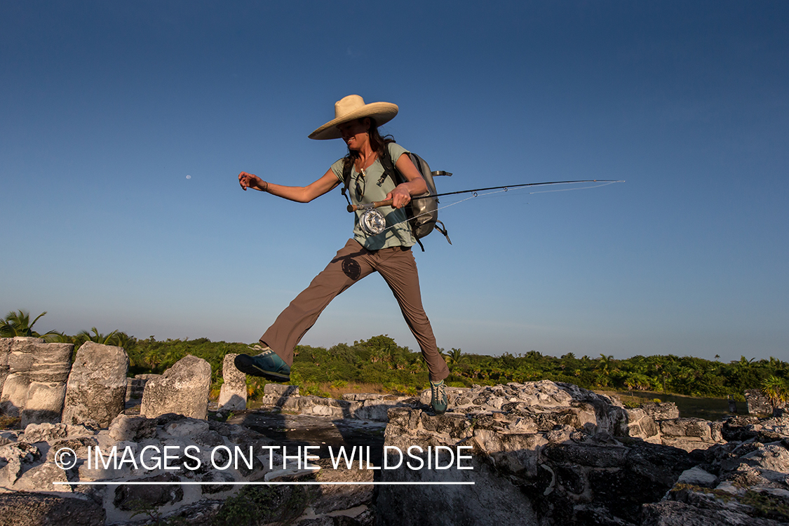 Flyfishing woman walking through ruins to fishing location.