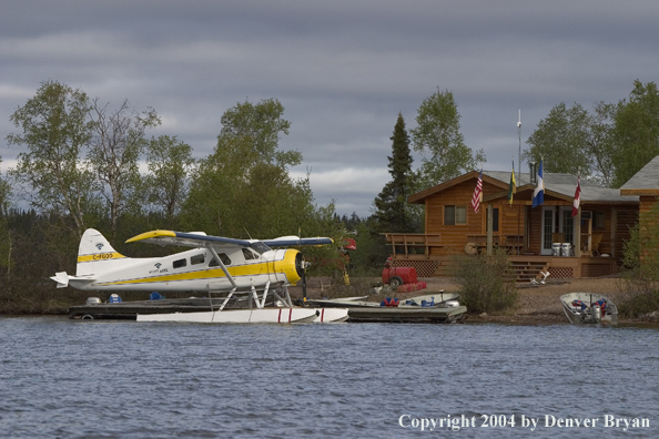 Float plane and fishing boats tied up to the dock in front of a fishing lodge.  Saskatchewan.