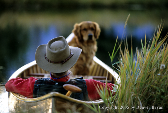 Flyfisherman with Golden Retriever in wooden cedar canoe.  