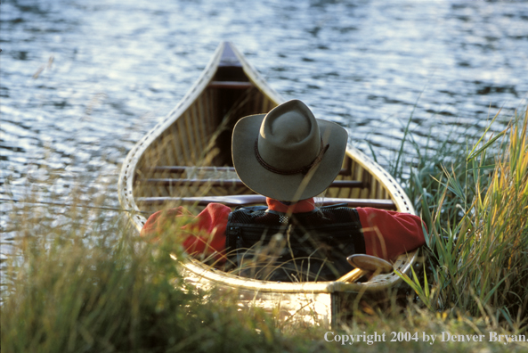 Flyfisherman in wooden cedar canoe.  Teton mountains in background.