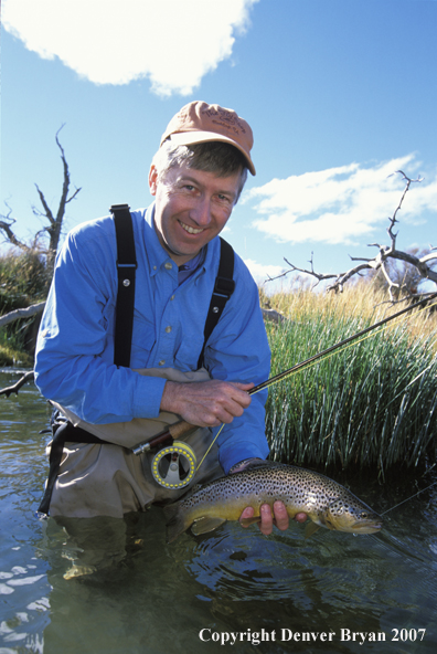 Flyfisherman holding brown trout.