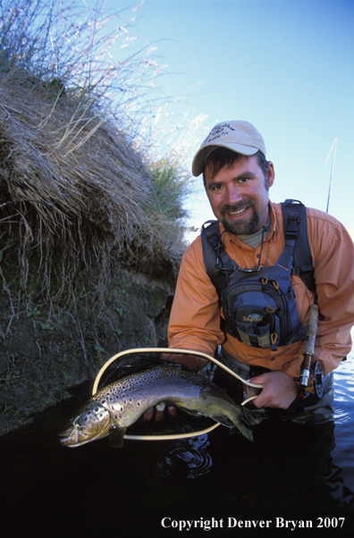 Flyfisherman holding brown trout.