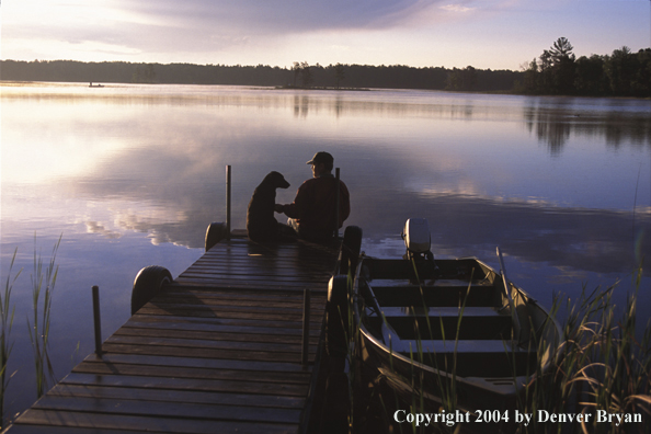 Spincast fisherman on dock with dog