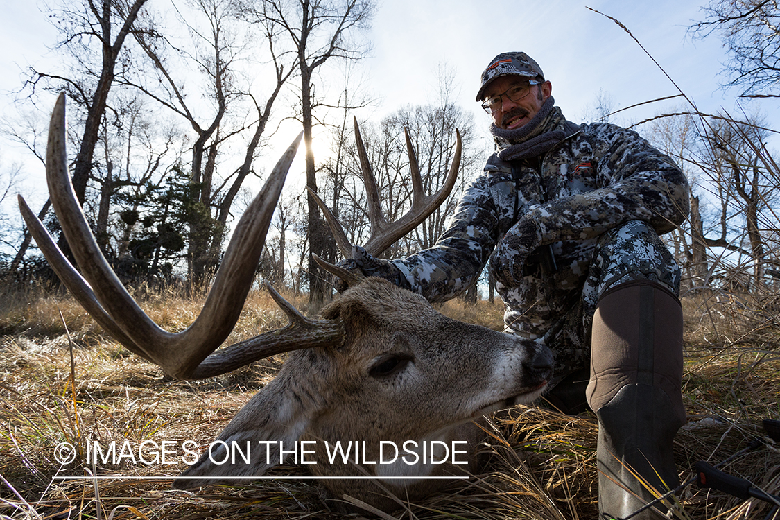 Bow hunter with downed white-tailed deer.