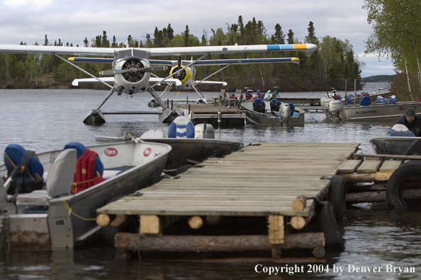 Float plane and fishing boats tied up to the dock at dusk.  Saskatchewan.