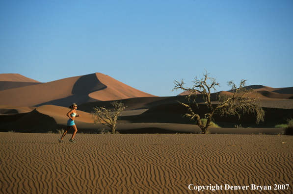 Woman running on sand dunes in Sossusvlei park, Namibia. Africa