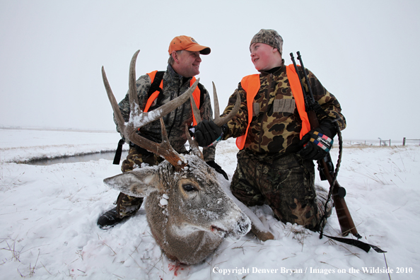 Father and son posing with son's downed white-tail buck 