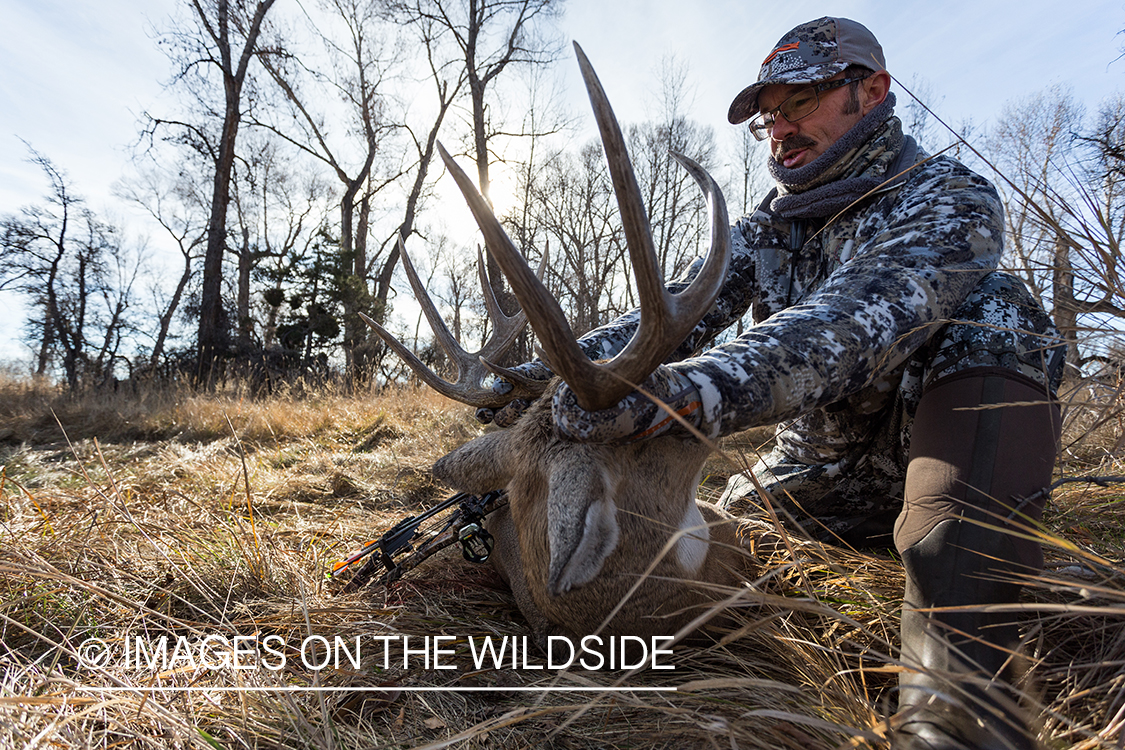 Bow hunter with downed white-tailed deer.