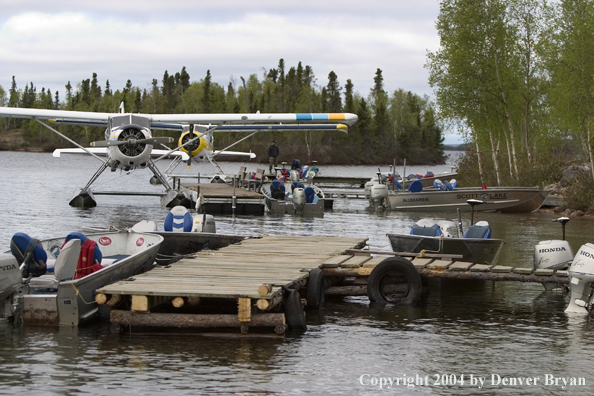 Fishermen with float plane and fishing boats tied up to the dock at dusk.  Saskatchewan.