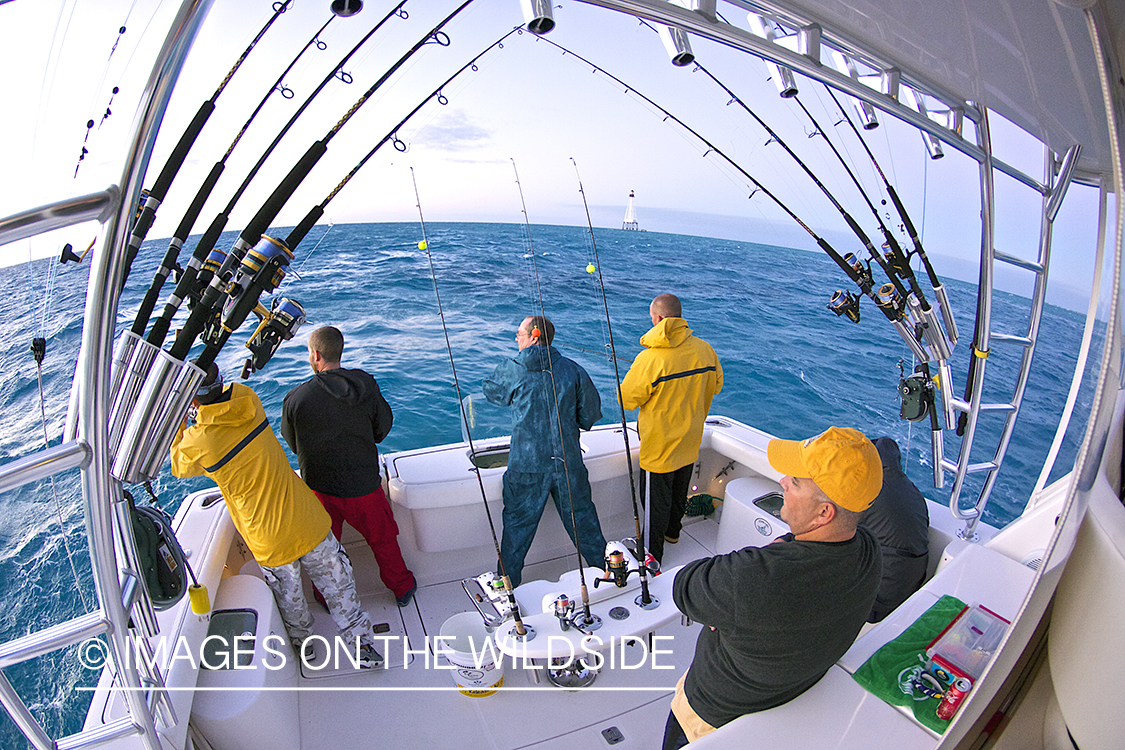 Fishermen on deep sea fishing boat with fishing rods.