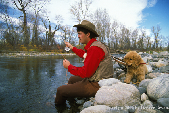 Flyfisherman casting with Golden retriver puppy pulling on net.