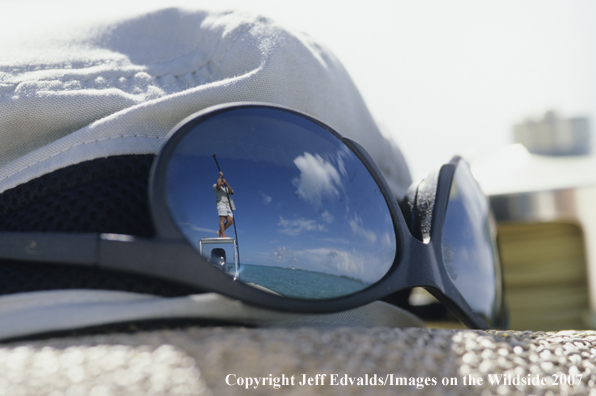 Reflection of Captain poling the flats boat for tarpon