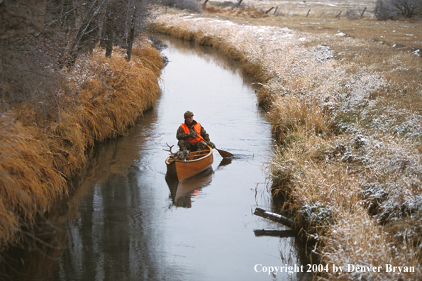 Hunter in canoe with bagged white-tailed deer.