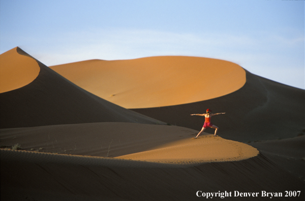 Woman stretching on sand dunes in Sossusvlei park, Namibia. Africa