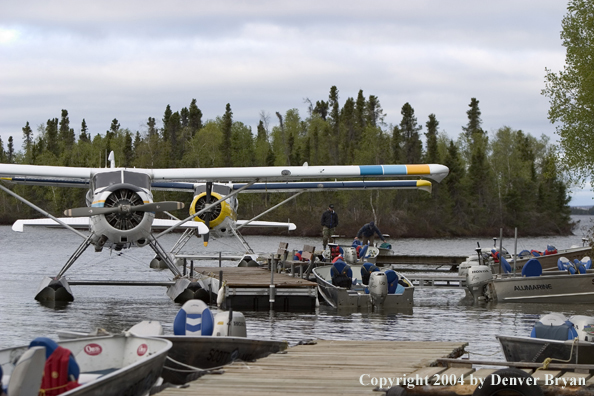 Fishermen with float plane and fishing boats tied up to the dock at dusk.  Saskatchewan.