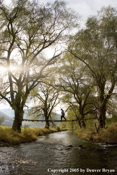 Flyfisherman crossing foot bridge over Pennsylvania spring creek.